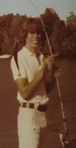 A man holding a stick and wearing white pants.