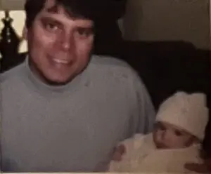 A man and baby in the bed of their car.