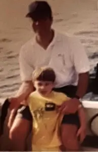 A man and boy sitting on the back of a boat.