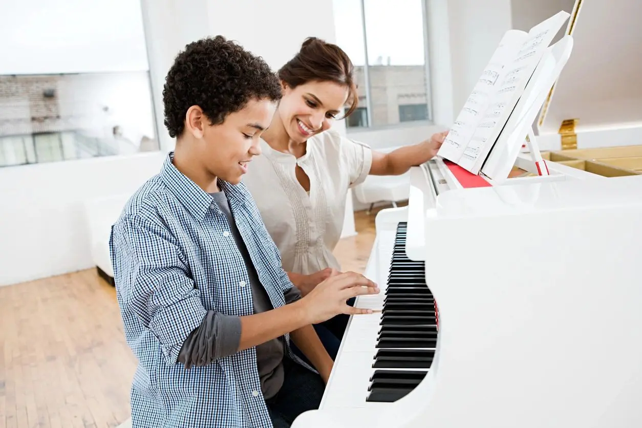 A woman and boy playing piano in an office.