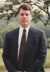 A man in a suit and tie standing outside.