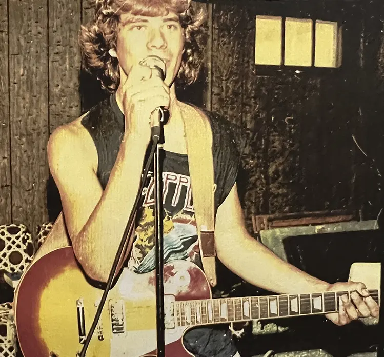 A man holding a microphone and playing guitar.