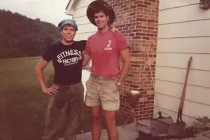 Two men standing next to each other in front of a brick building.